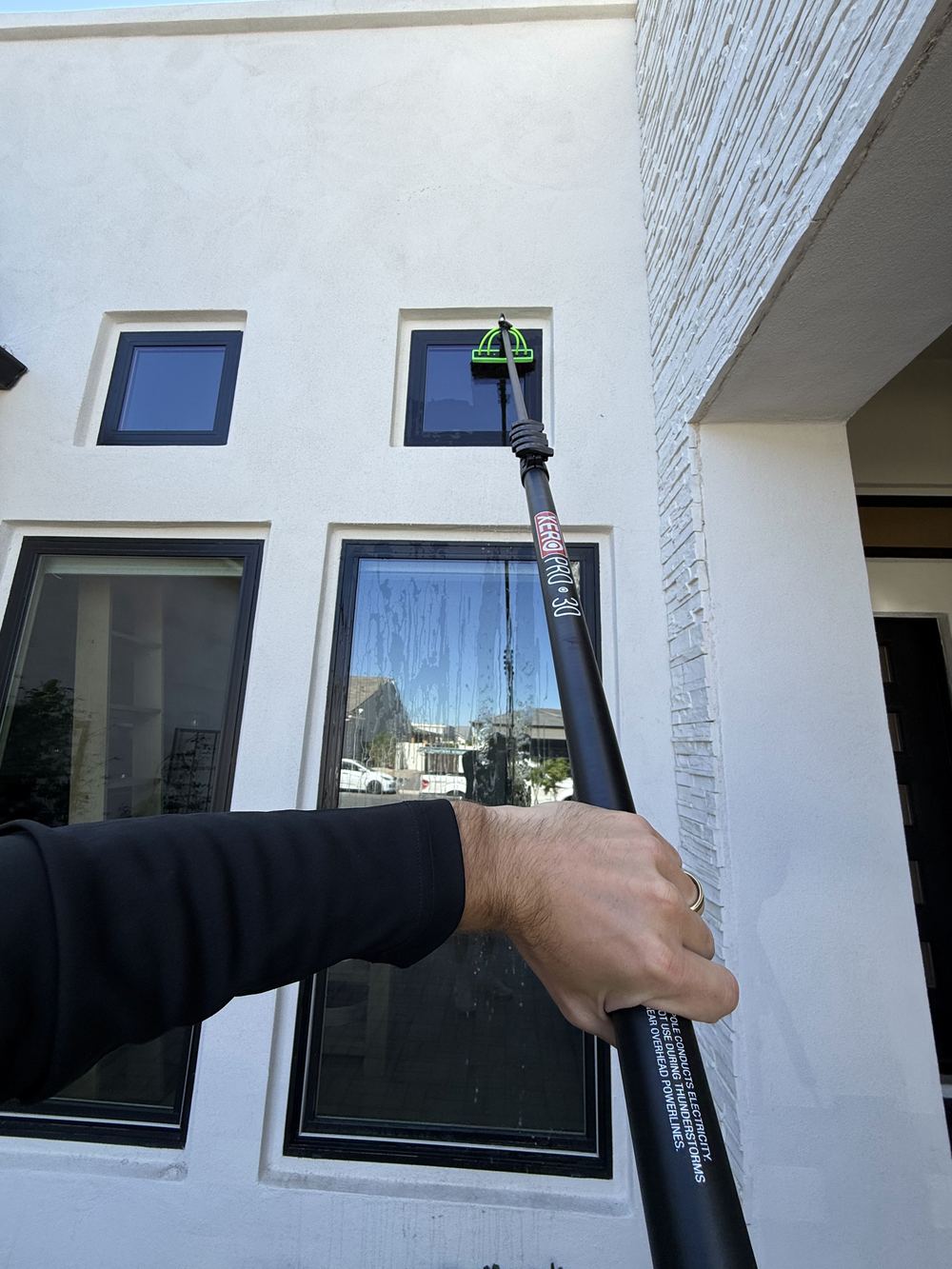 Apex Power Washing technician cleaning exterior windows with a water-fed pole